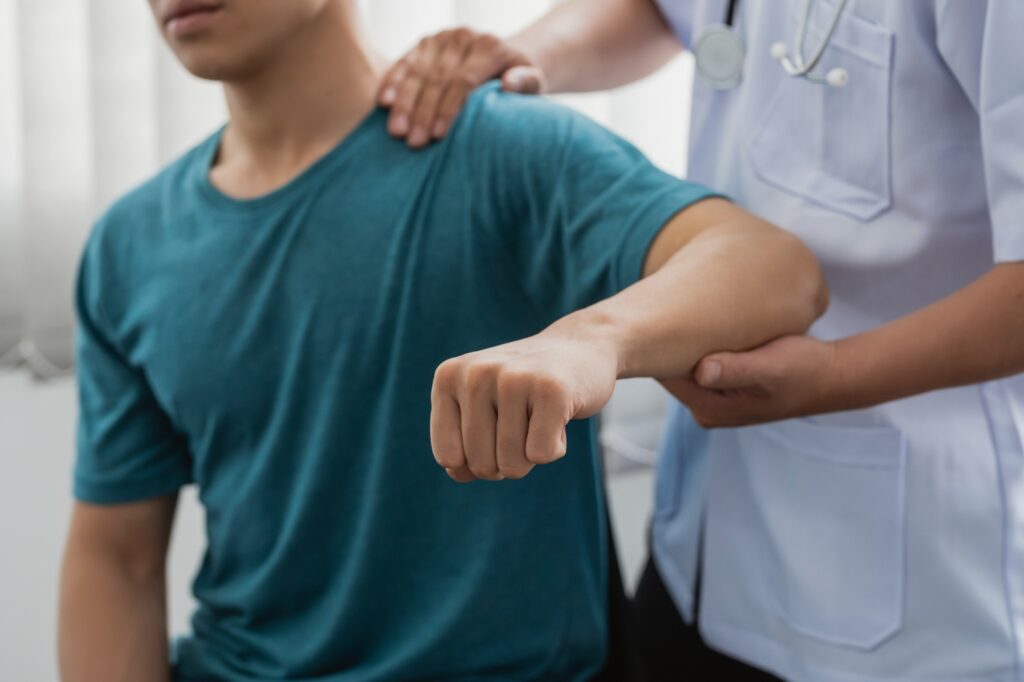 läker med person som undersöker arm och axel